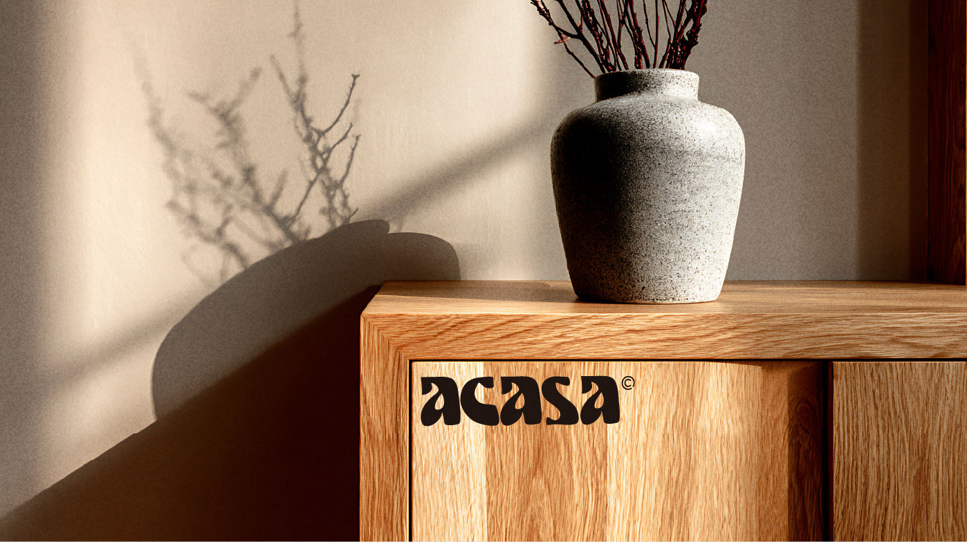 Mise en situation Acasa : wordmark gravé sur un meuble en chêne, vase et lumière rasante
